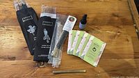 Full lot displayed on wooden table including four Maskeraide Matcha Detoxifying Clay face mask sachets, several wrapped incense sticks, a black incense holder, and a small dark dropper bottle of face oil.
