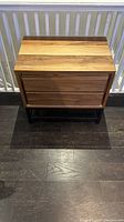 Front view showing the natural wood tabletop with visible wood grain and the two drawers closed.