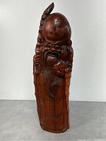 Front angled view of the carved bamboo Shou figure showing facial features, staff, and peach details.