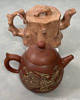 Photo showing both teapots together; tree trunk style and rounded dragon design teapot