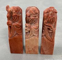 Front view of three hand-carved Shoushan stone seals with figures on top showing detailed carving and coloration.