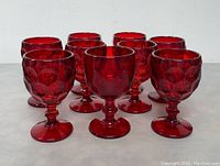Eight Viking Glass Georgian ruby red goblets arranged in two rows on a white surface, showing the front and side views of the honeycomb pattern on the bowls.