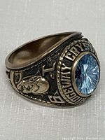 Side view showing engraved figure head and part of blue stone with Ridgeway Crystal Beach text.