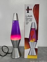 Photo of the classic lava lamp next to its box showing lamp and branding with product details and dimensions.