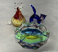 Front view of the clear glass cat, blue glass cat, and multifaceted glass paperweight together