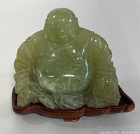 Front view of light green jade Buddha figurine with detailed carving and smiling face.