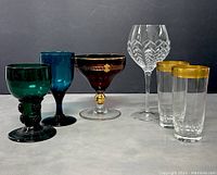 Group photo of seven vintage glasses showing colors, shapes, and decorative details including gold bands and etched designs.