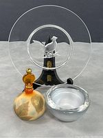 Photo of clear glass plate with etched pheasant centered behind white milky glass bowl and amber stopper vintage perfume bottle