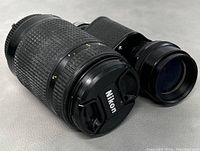 Spiratone monocular and Nikon camera lens side by side showing condition and details