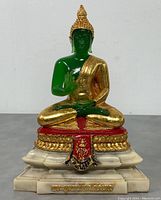 Front view of the 10.5 inch green and gold Thai Buddha seated statue on marble-like base with red and gold decorative elements.