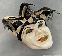 Front view of the handmade jester face mask showing black and beige diamond pattern with bells and painted facial features.