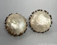 Pair of vintage round clip-on earrings, domed silver-tone center with gold-tone metal prongs around edges.