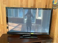 Front view of Panasonic flat-screen TV on wooden table with remote control visible