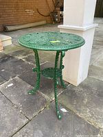 Full side view of green cast aluminum end table highlighting ornate legs and small shelf
