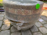 Exterior of large ceramic planter pot partially wrapped in bubble wrap showing textured and painted ceramic surface.