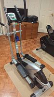 Full view of the ION E300 elliptical machine showing the entire machine including the pedals, handles, and base on a floor mat.