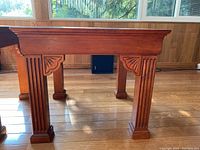 Side view showing fluted legs and carved decorative woodwork on an end table.
