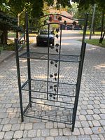 Front view of folding metal shelf showing decorative grape vine pattern and the three wire grid shelves.