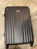 Exterior photo of black hard shell suitcase, showing textured vertical ridge design and Samsonite logo plate
