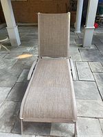 Front view of outdoor lounge chair with beige fabric and metal frame, showing full length and upright backrest.