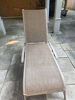 Front view of the outdoor lounge chair on stone tile patio.