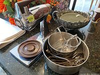 Photo of Sunbeam electric stand mixer unit on counter with two mixing bowls and metal beaters and whisks inside bowls