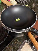 Top view of the two stacked woks showing the new or lightly used black non-stick interior and natural wood handle.