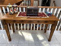 Front view of wood console table with items on top showing overall structure and finish.