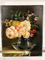 Full view of an oil painting on canvas showing a floral bouquet in a glass vase on a dish, signed in red at the bottom right.