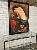 Full view of the large framed oil painting showing a nude woman sitting with her back exposed, draped in blue fabric, on glass table against tiled wall.