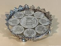 Angled view showing entire dish, coin arrangement, decorative rim and visible feet