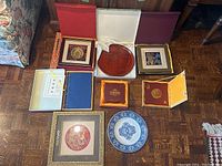 Multiple Chinese decorative framed art pieces and decorative plates in gift boxes.
