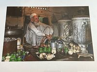 Photo showing the complete view of the photograph featuring the tea seller with the clustered traditional metal teapots and samovars.