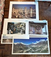 Overview photo showing all five photographic prints laid out together on a wooden floor, capturing sizes, colors, and subject variety of the prints.