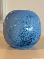 Angled front view of spherical blue glass vase showing overall shape and bubble pattern