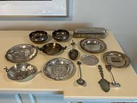 Wide view of all 14 silver and silver-plated pieces arranged on a table