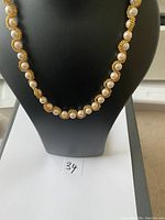 Full view of the necklace displayed on a black mannequin bust showing the gold-tone chain with evenly spaced faux pearls wrapped in twisted rope detail