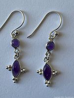 Front view of pair of sterling silver earrings with amethyst stones, showing round top and marquise bottom stones with silver beads.