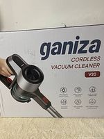 Photo of front of box showing Ganiza Cordless Vacuum Cleaner V20 branding and features icons such as ultra-strong suction power, multi-surface cleaning, long battery life, low noise operation, high-powered motor, LED lights on main cleaning head.