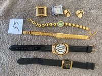 Full view of all watches, bracelet, and cufflinks laid out on textured fabric.