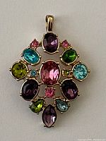 Front view of pendant with colorful stones in different shapes and sizes set in gold-tone metal.