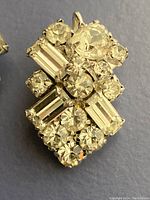 Close-up of one Sherman earring showing clear round and baguette rhinestones set in gold-tone metal.