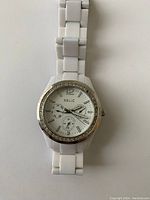 Front and side view of the white ceramic band Relic watch with crystal bezel and functioning analog dial.