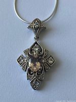 Detailed view of the sterling silver pendant with clear faceted central gemstone and ornate filigree design