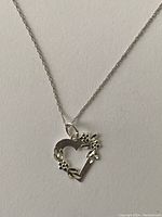 Close-up photo of the sterling silver heart pendant necklace showing the floral details on the open heart pendant.