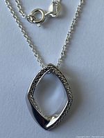Photo showing spring ring clasp and part of the fine linked chain with the open marquise-shaped pendant