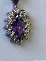 Close-up of necklace pendant showing marquise-cut amethyst with surrounding clear stones set in sterling silver.