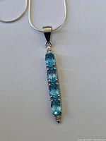 Close-up of the pendant showing four blue topaz gemstones in sterling silver setting.