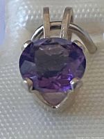 Close-up image of the oval faceted amethyst stone set in a sterling silver pendant with prong setting and loop bail.