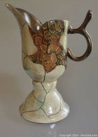 Front right side view of the ceramic hand painted water pitcher showing textured geometric design and curved handle.